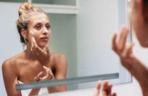 Femme devant un miroir qui hydrate sa peau