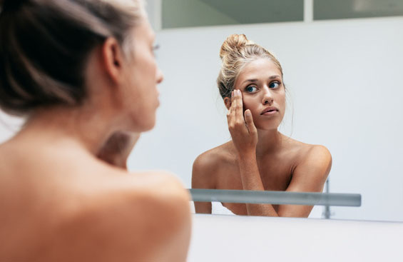 Femme devant un miroir qui nourrie sa peau